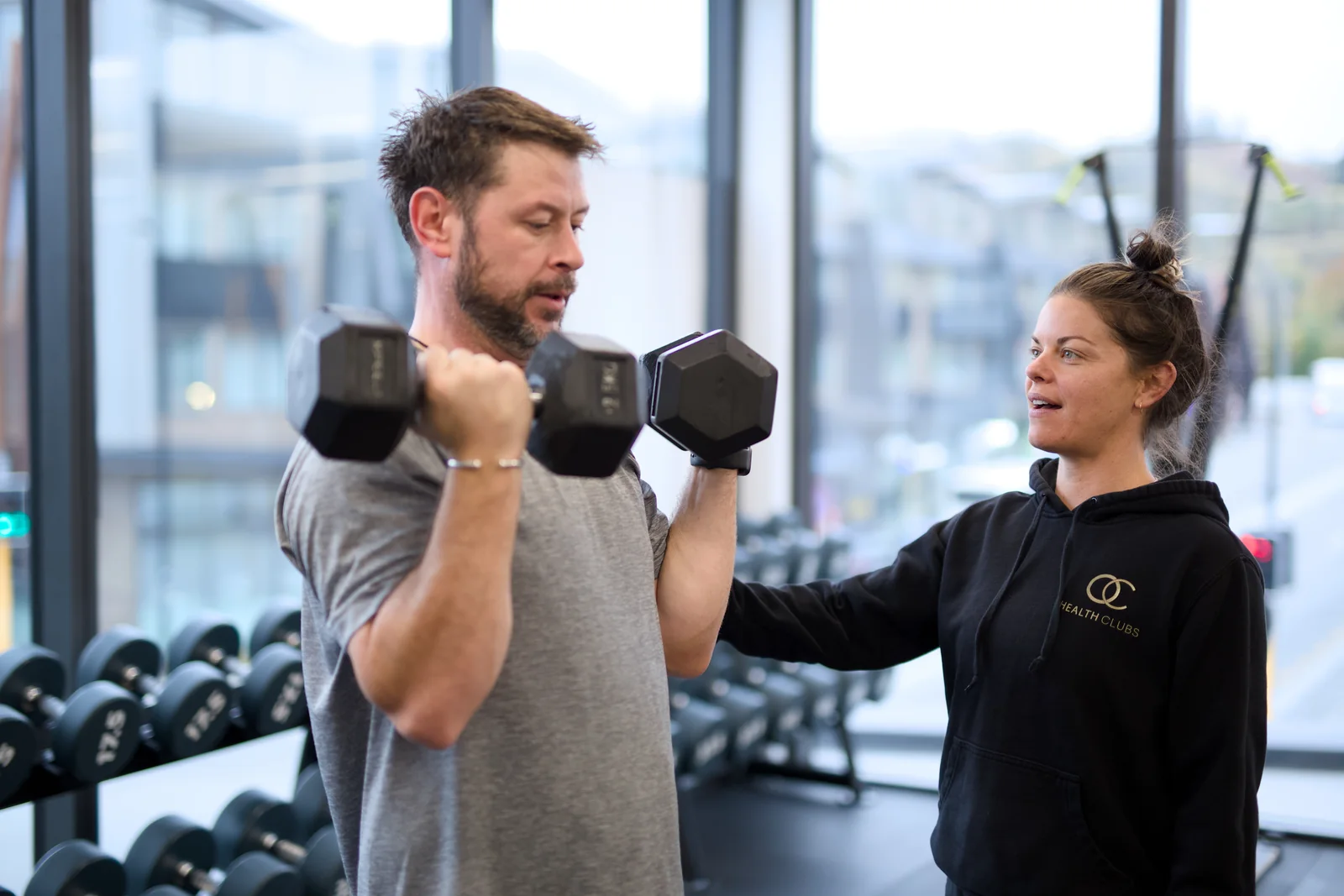An OC coach guiding a member through a strength exercise